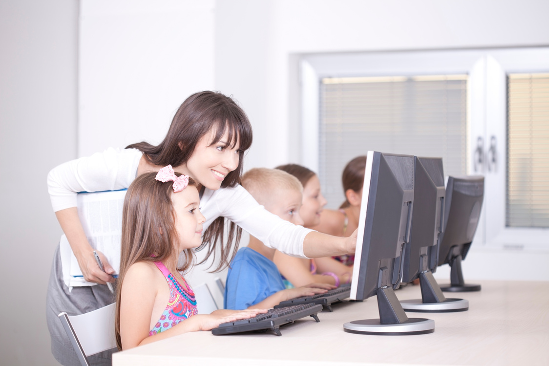 Teacher helping children with computers